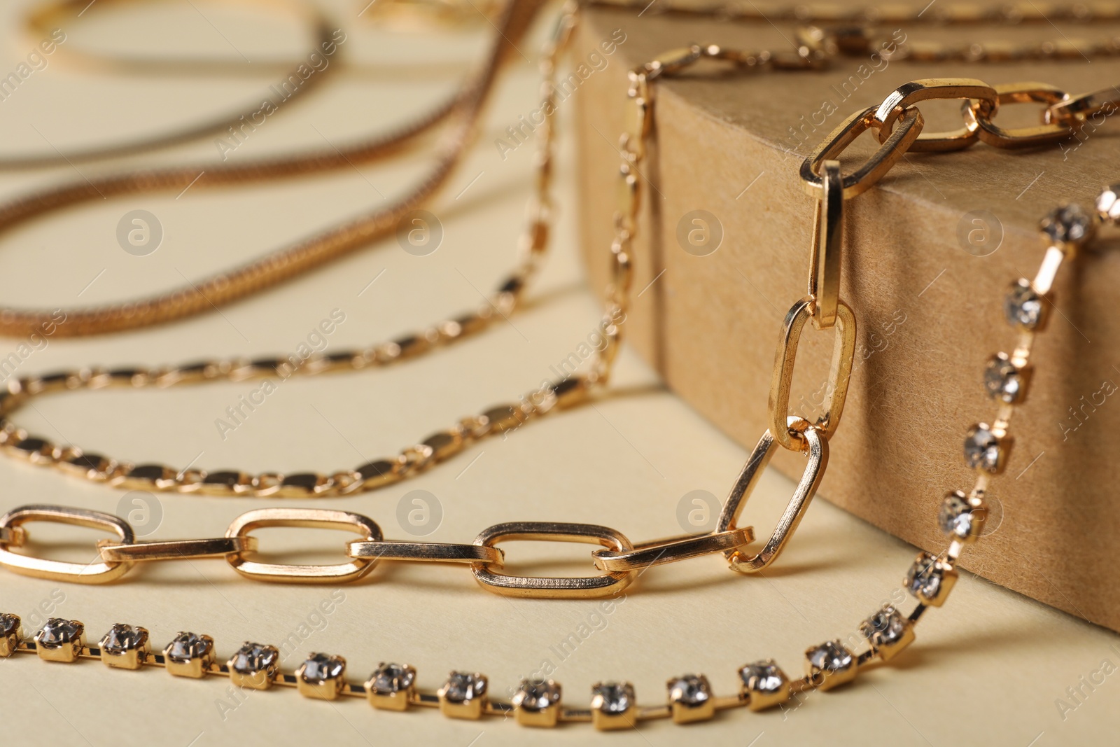 Photo of Different metal chains on beige background, closeup. Luxury jewelry