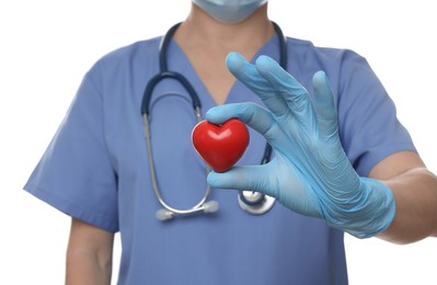 Doctor wearing light blue medical glove holding decorative heart on white background, closeup