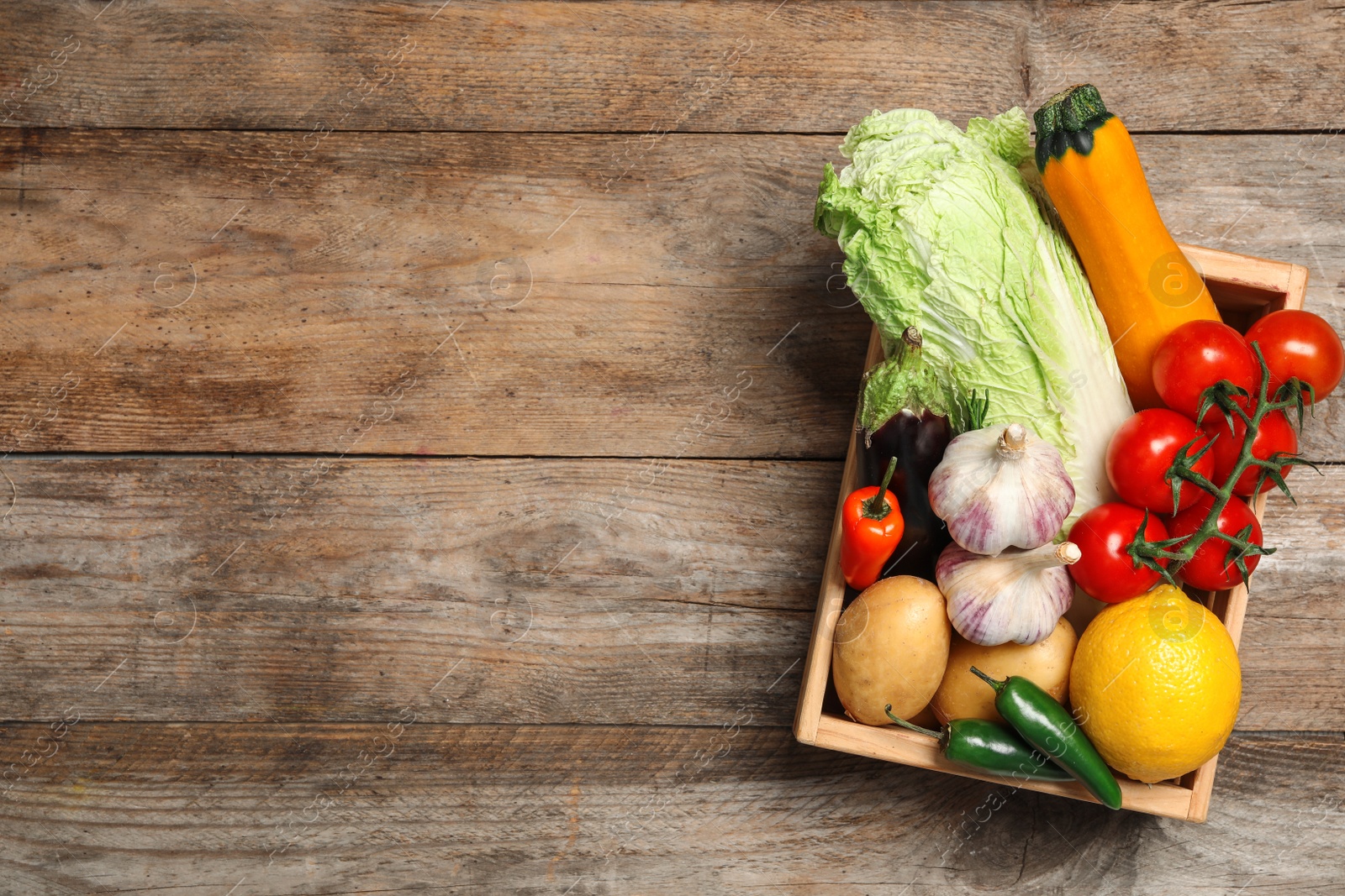 Photo of Fresh vegetables in crate on wooden background, top view. Space for text