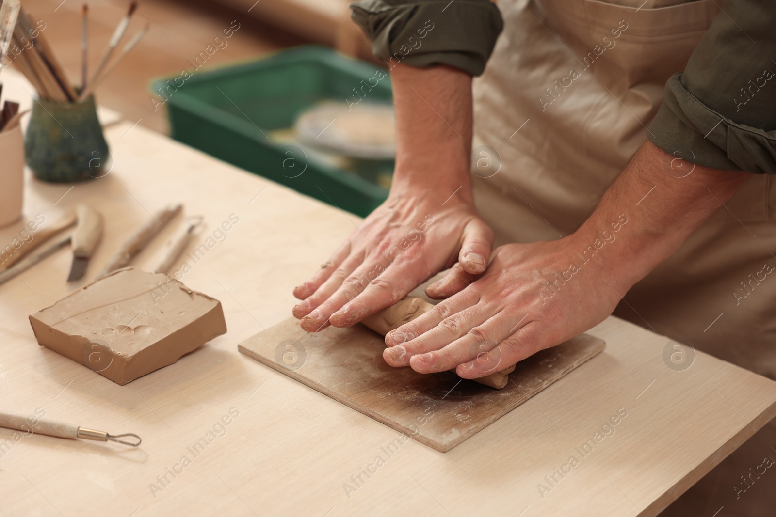 Photo of Man crafting with clay at table indoors, closeup