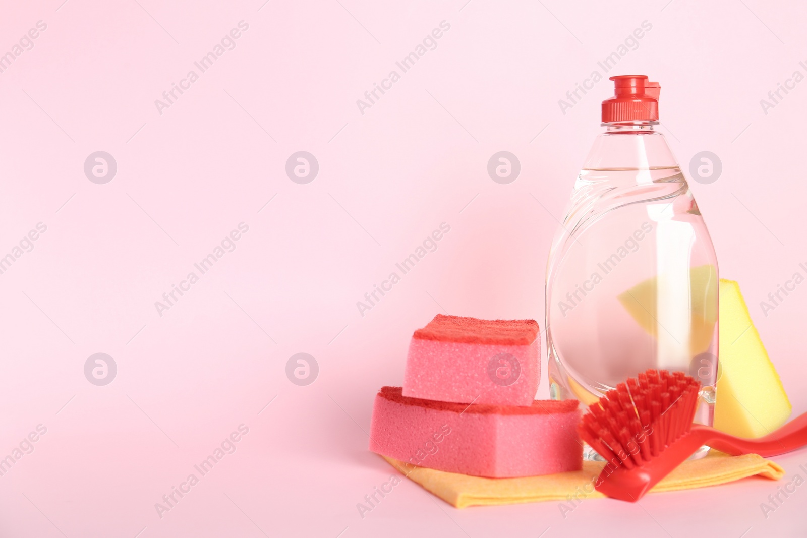 Photo of Cleaning product and tools on pink background, space for text. Dish washing supplies