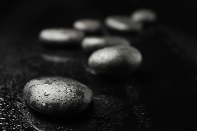 Photo of Wet spa stones on black background. Space for text