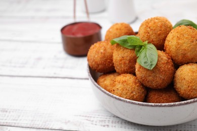 Photo of Bowl of delicious fried tofu balls with basil on white wooden table, closeup. Space for text