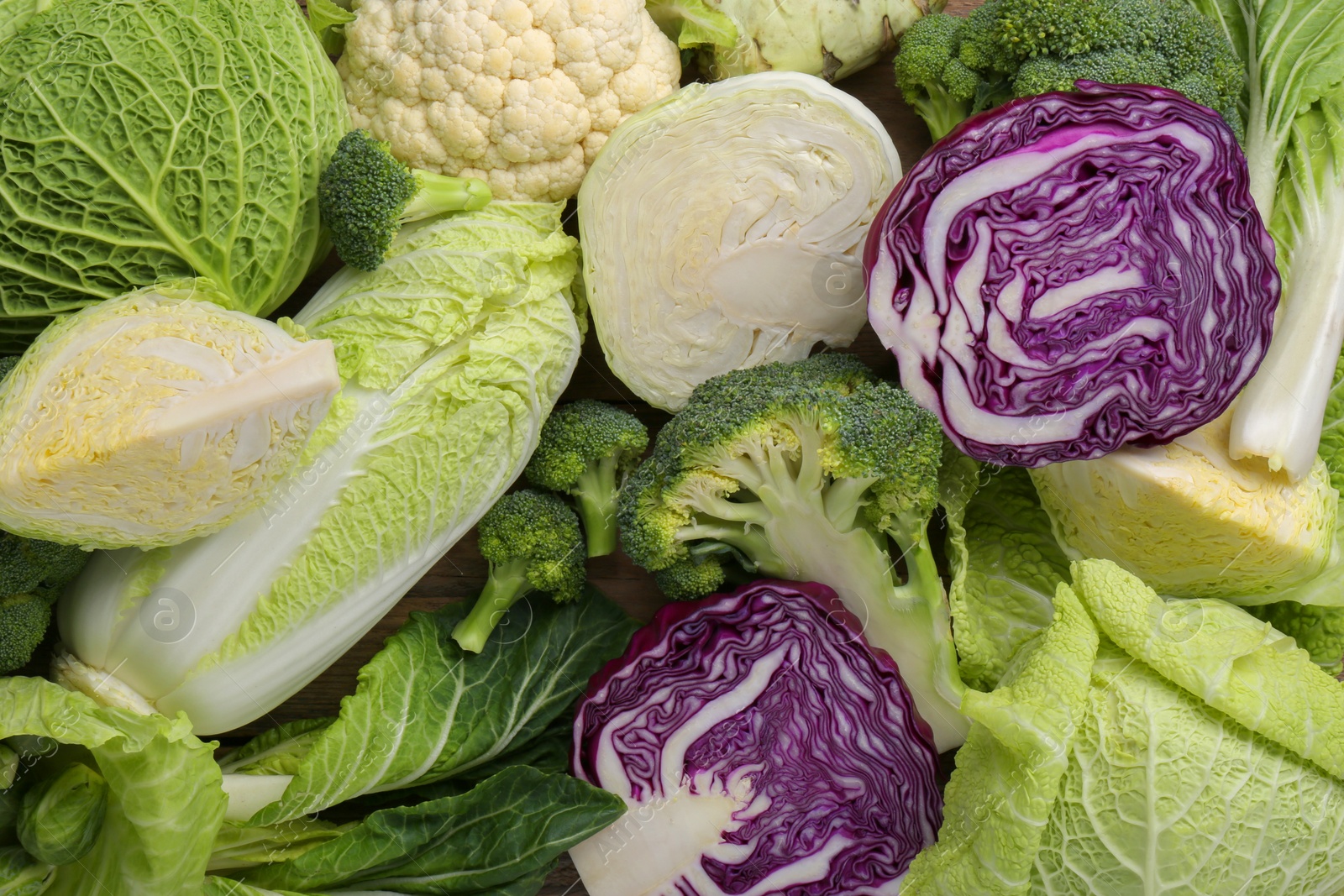 Photo of Different whole and sliced types of cabbage as background, top view