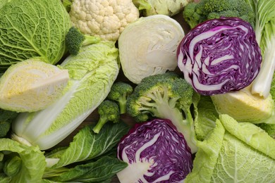 Photo of Different whole and sliced types of cabbage as background, top view