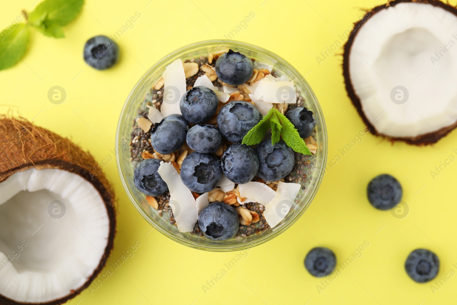 Photo of Tasty oatmeal with smoothie, blueberries, coconut and mint on yellow background, flat lay. Healthy breakfast