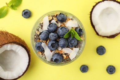 Tasty oatmeal with smoothie, blueberries, coconut and mint on yellow background, flat lay. Healthy breakfast