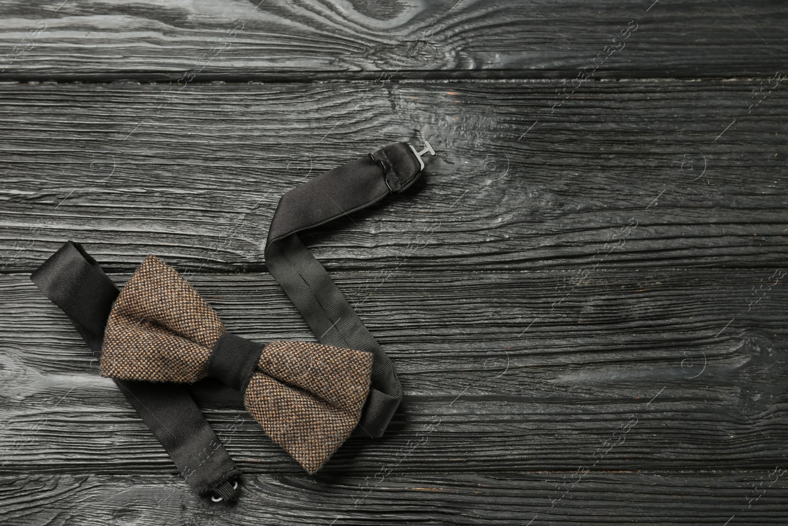 Photo of Stylish bow tie on black wooden background, top view. Space for text