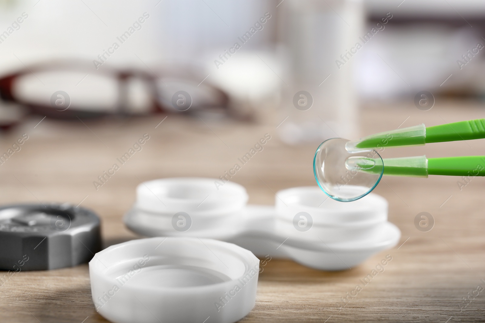 Photo of Taking contact lens from case with tweezers, closeup
