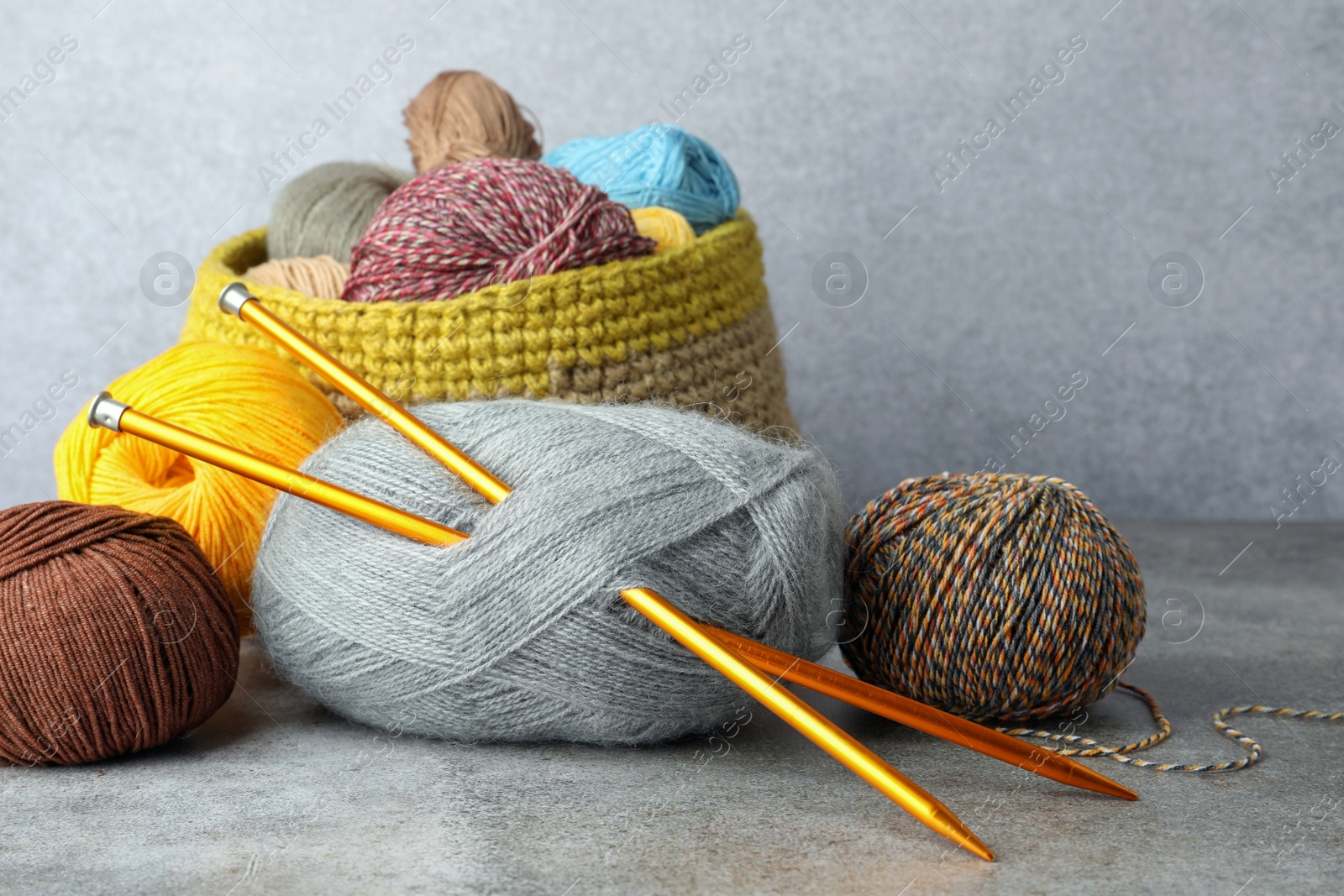 Photo of Soft woolen yarns and knitting needles on grey table