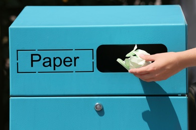Photo of Woman throwing crumpled paper into sorting bin on city street, closeup. Recycling waste