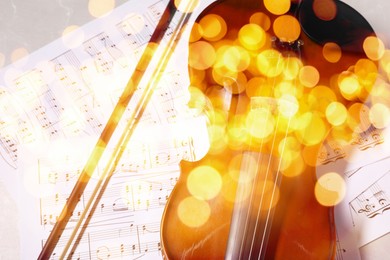 Image of Christmas and New Year music. Violin and music sheets on light background, bokeh effect