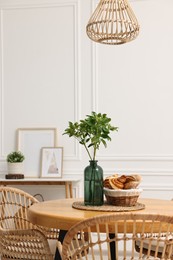 Photo of Dining room interior with comfortable furniture and green branches