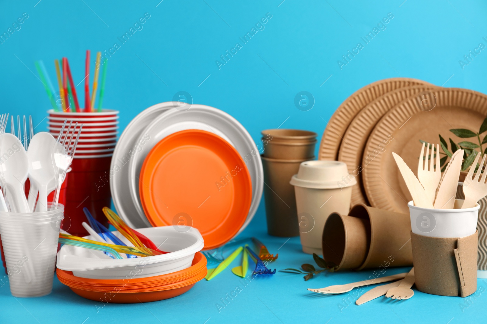 Photo of Plastic and eco disposable tableware on light blue background