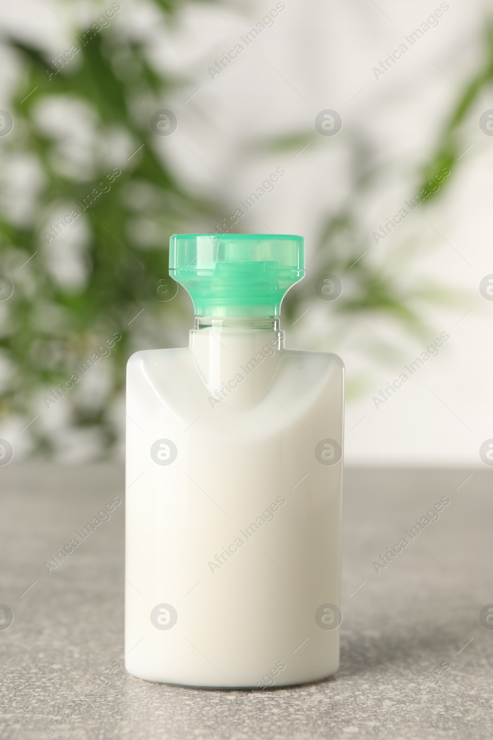 Photo of Mini bottlecosmetic product on light grey table against blurred background