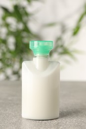 Mini bottle of cosmetic product on light grey table against blurred background