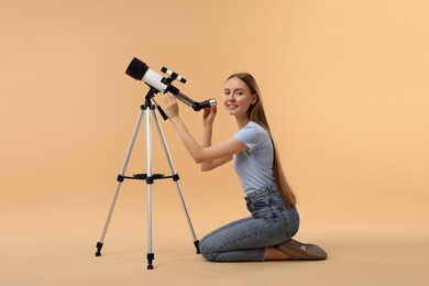 Photo of Happy astronomer with telescope on beige background