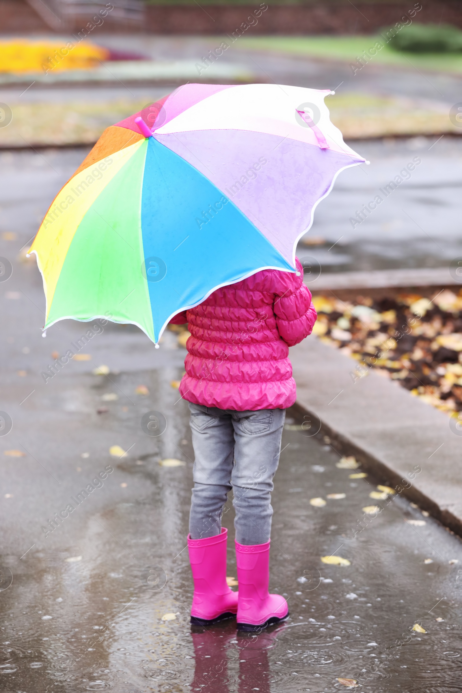 Photo of Little girl with umbrella taking autumn walk in city on rainy day