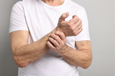Photo of Arthritis symptoms. Man suffering from pain in wrist on gray background, closeup