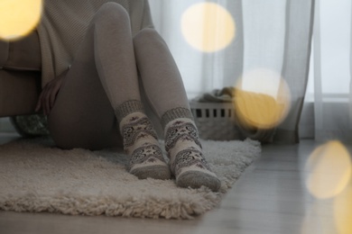 Woman wearing knitted socks at home, closeup. Warm clothes