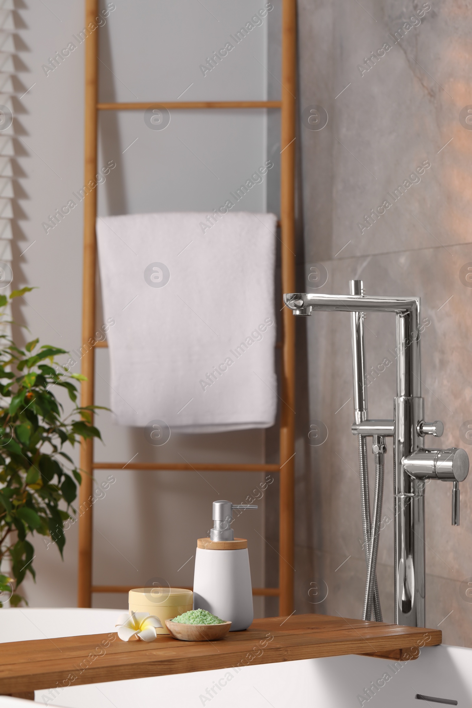 Photo of Spa products and beautiful flower on wooden tub tray in bathroom