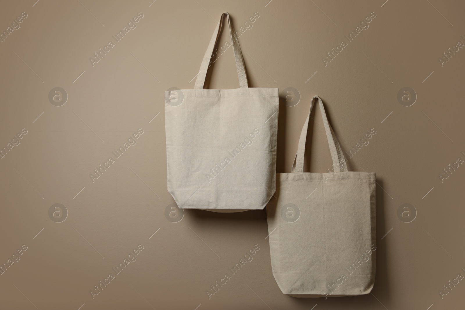 Photo of Eco tote bags hanging on color wall. Space for design