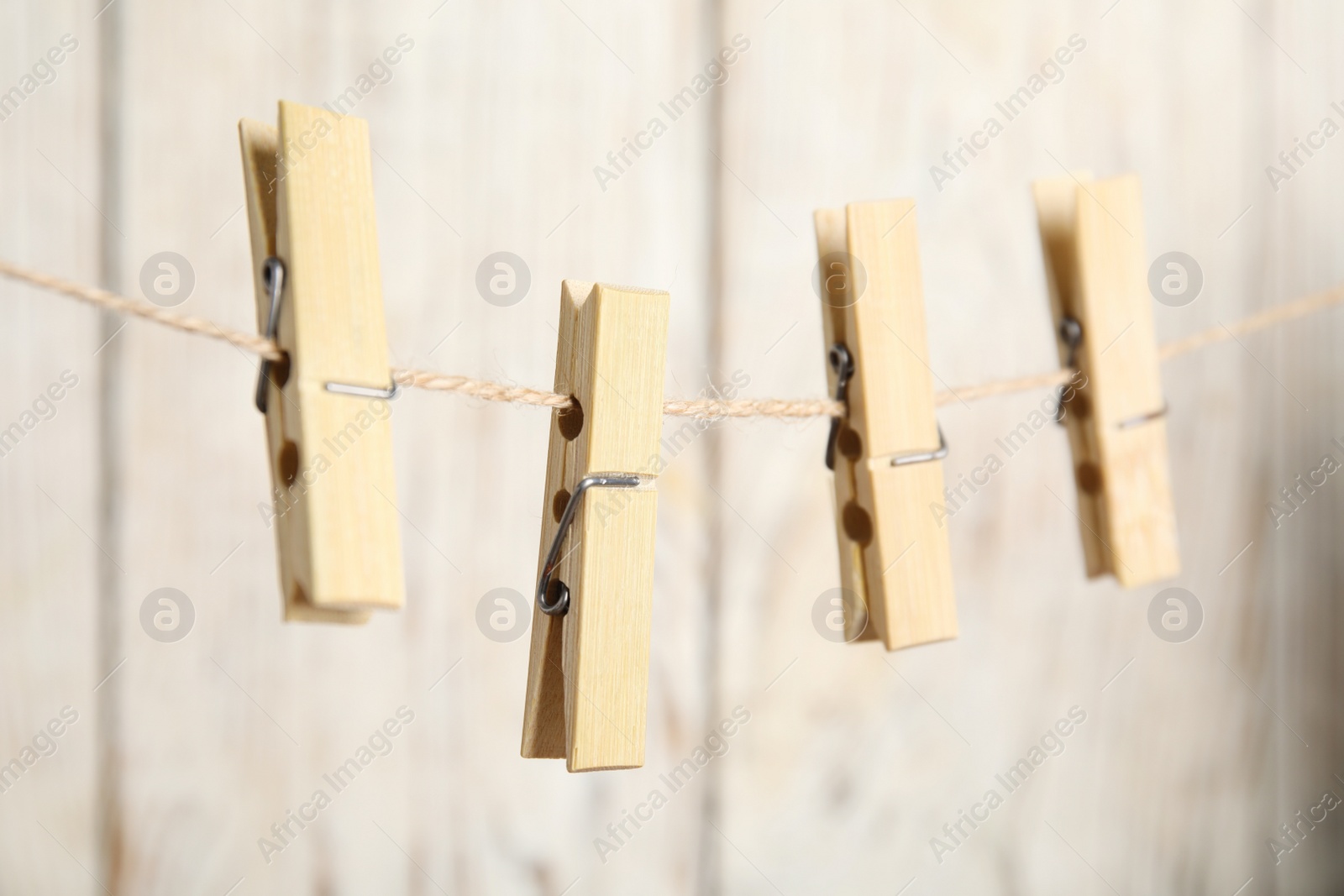 Photo of Clothespins on rope against white wooden background, closeup