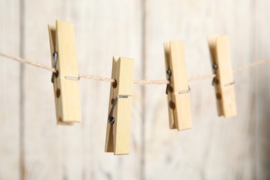Photo of Clothespins on rope against white wooden background, closeup