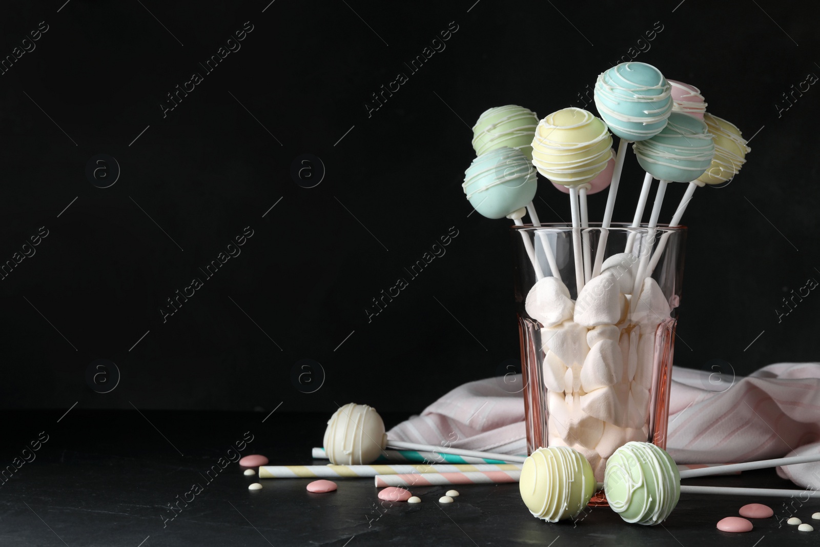 Photo of Sweet cake pops on table against black background. Space for text