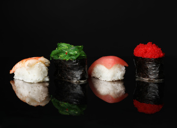 Photo of Set of delicious sushi on black mirror surface