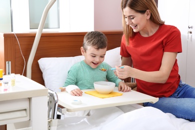 Woman feeding her little child with soup in hospital