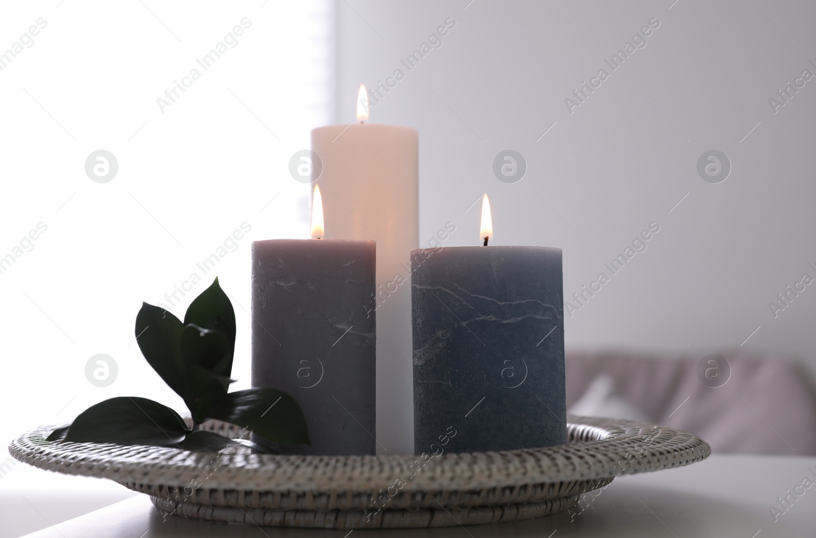 Photo of Tray with burning candles and leaves on white table indoors