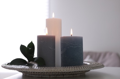 Tray with burning candles and leaves on white table indoors