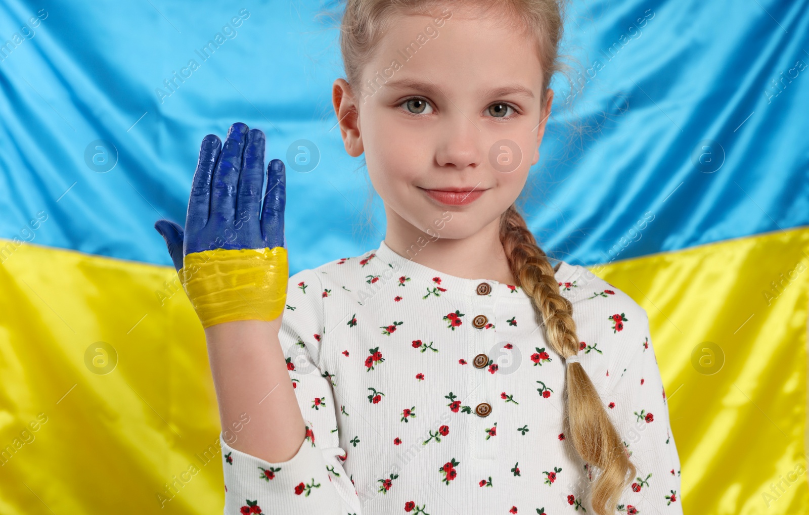 Photo of Little girl with paint on hand near Ukrainian flag