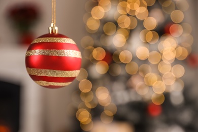 Beautiful holiday ornament hanging against blurred Christmas lights