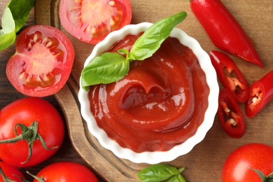 Photo of Bowl of tasty ketchup and ingredients on wooden table, flat lay