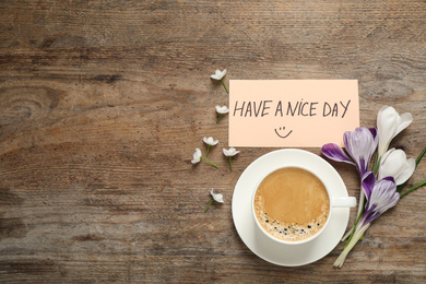 Photo of Morning coffee, flowers and card with HAVE A NICE DAY wish on wooden table, flat lay. Space for text