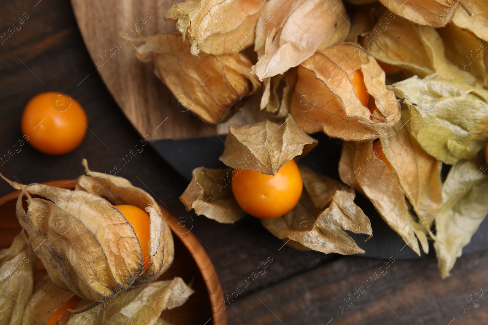 Photo of Ripe physalis fruits with calyxes on wooden table, flat lay