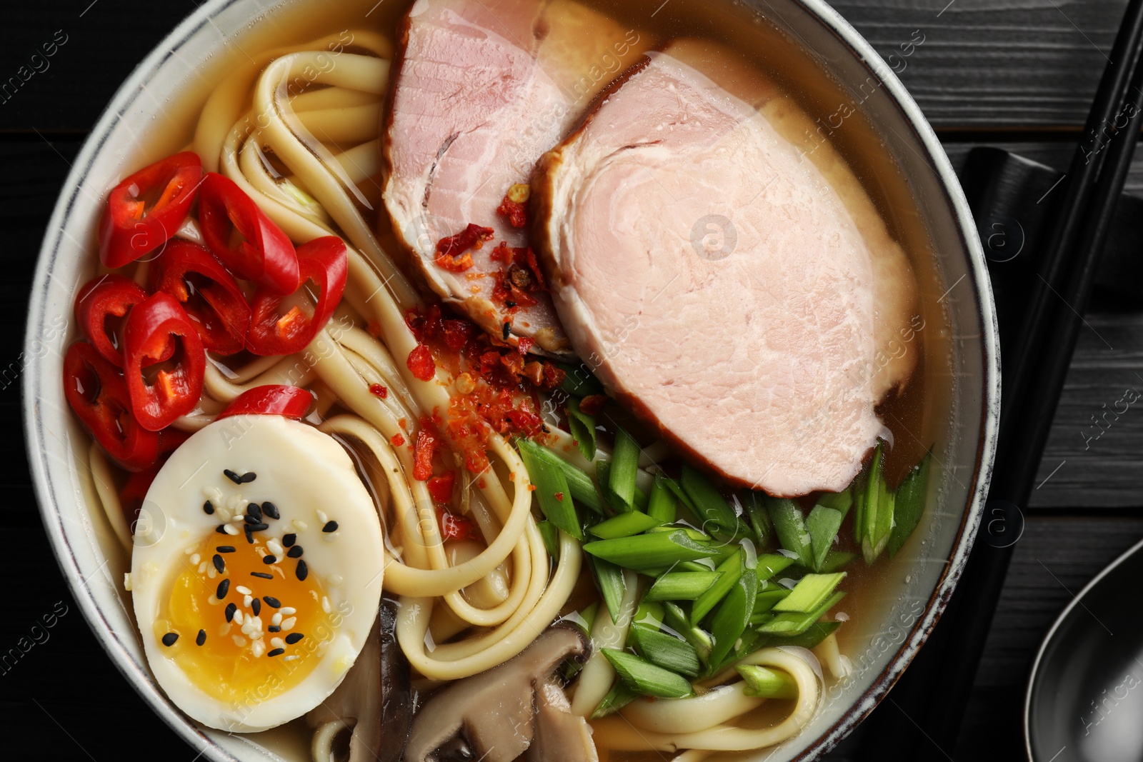 Photo of Delicious ramen in bowl on black table, top view. Noodle soup