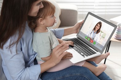 Image of Mother and daughter having online consultation with pediatrician via laptop on sofa at home
