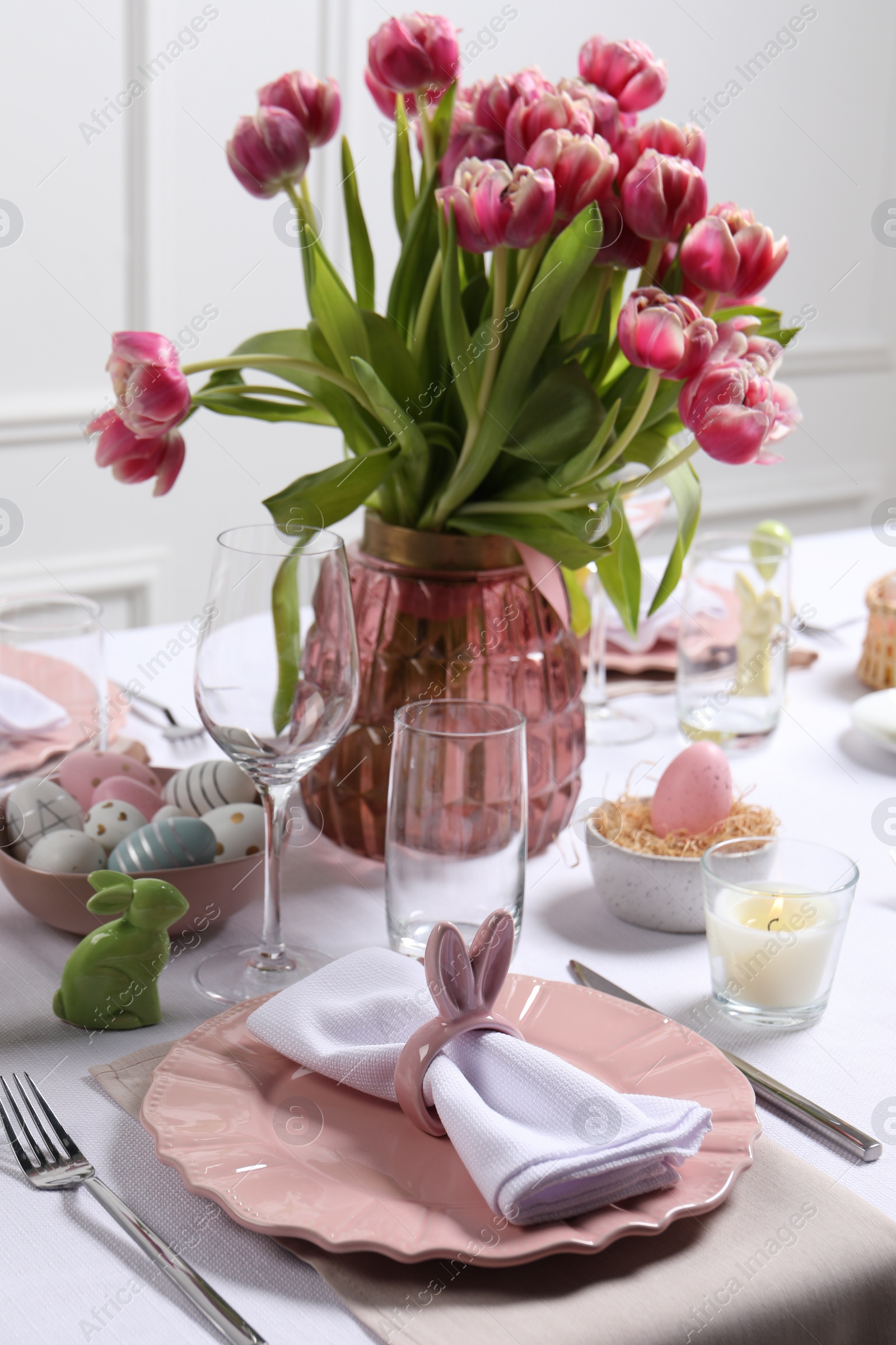 Photo of Festive table setting with napkin ring in shape of bunny ears. Easter celebration