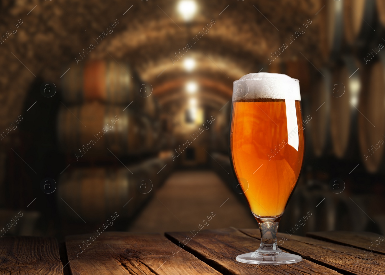 Image of Glass of tasty beer on wooden table in cellar with large barrels, space for text