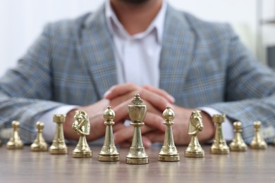 Man with chess pieces at wooden table, closeup