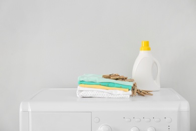 Photo of Bottle of detergent and children's clothes on washing machine