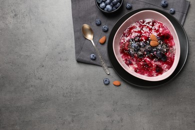 Photo of Tasty oatmeal porridge with toppings on grey table, flat lay. Space for text