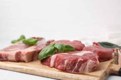 Photo of Cut fresh beef meat with basil leaves on wooden board, closeup