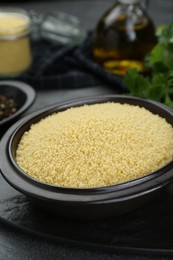 Photo of Bowl of raw couscous on grey table, closeup