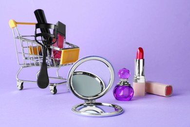 Photo of Stylish pocket mirror and makeup products on lilac background