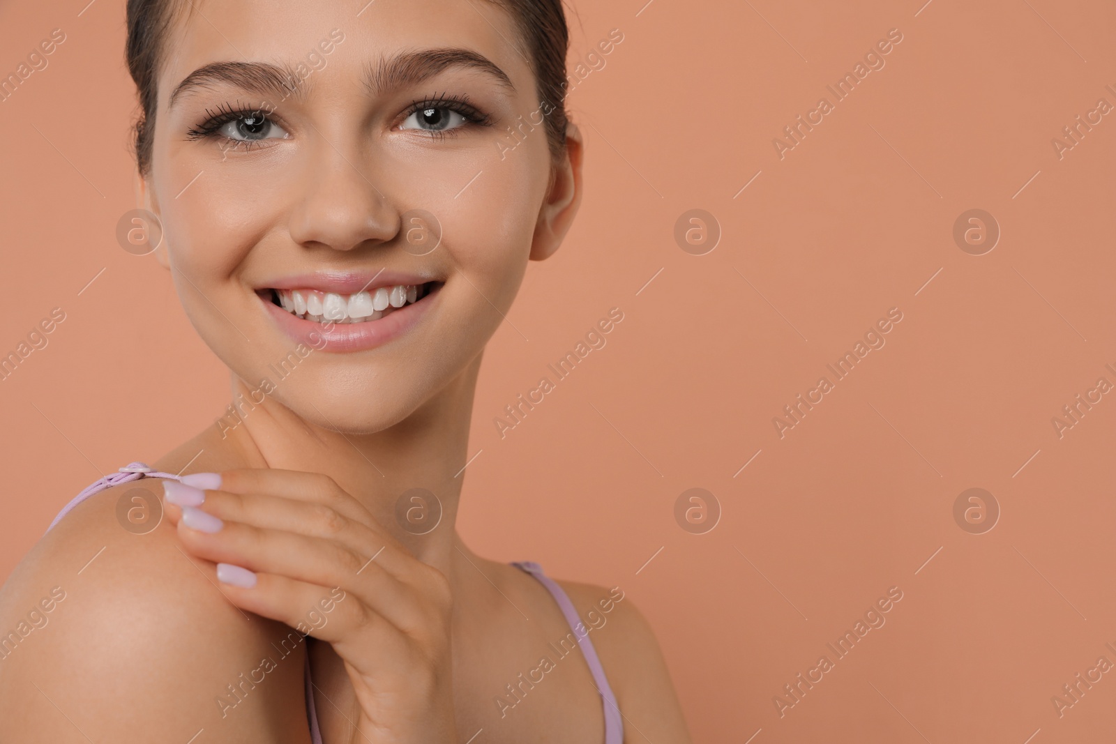 Photo of Pretty girl on pale coral background, space for text. Beautiful face with perfect smooth skin