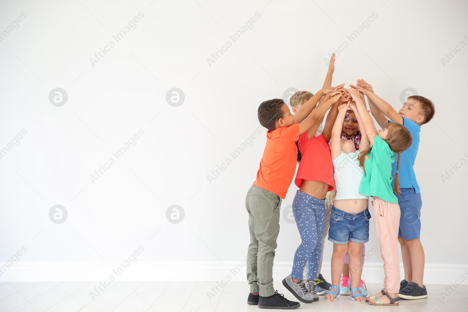 Photo of Little children putting their hands together on light background. Unity concept